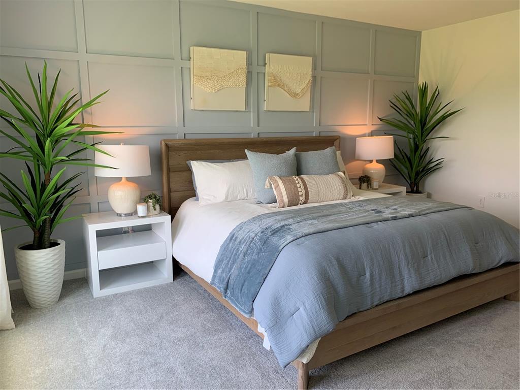 A bedroom features a wooden bed frame against a blue paneled wall with two plants — 5162 WORCHESTER DRIVE, KISSIMMEE, FL