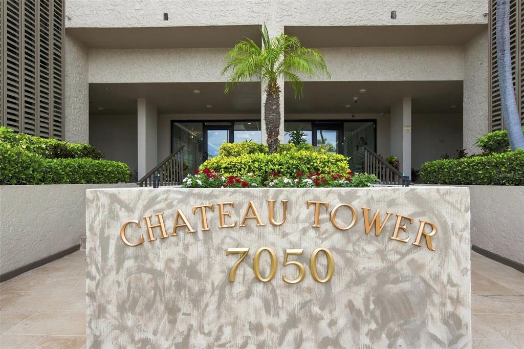 The exterior entrance of a building features a stone sign reading Chateau Tower 7050 — 7050 SUNSET DRIVE S UNIT 610, SOUTH PASADENA, FL
