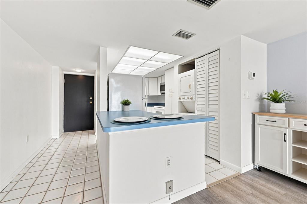 A kitchen features a blue-topped island, white cabinetry, a laundry closet, and tiled flooring — 7050 SUNSET DRIVE S UNIT 610, SOUTH PASADENA, FL