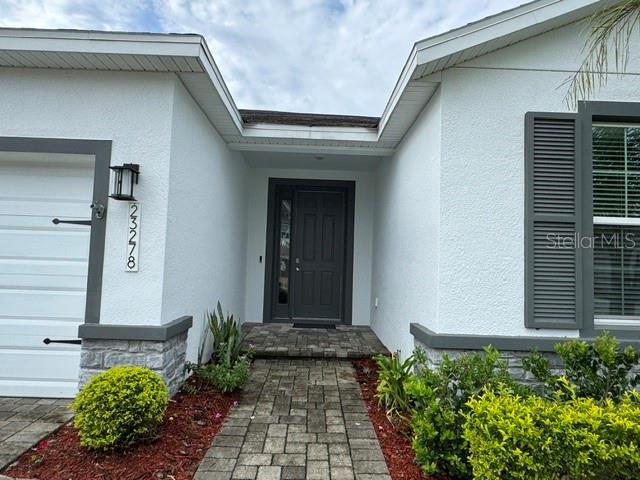 The exterior of a house features a gray front door, stone accents, and a paved walkway — 23278 SCAGLIONE DRIVE, LUTZ, FL