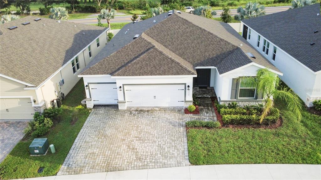A white house with a two-car garage and a paved driveway under a blue sky — 23278 SCAGLIONE DRIVE, LUTZ, FL
