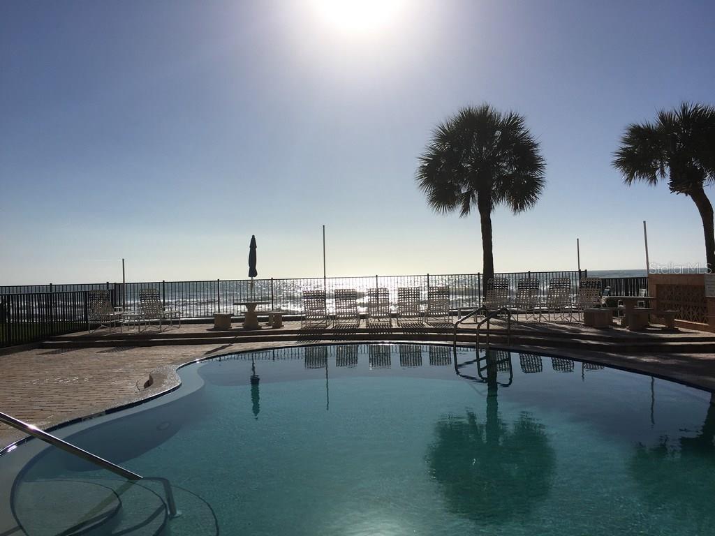 A swimming pool overlooks the ocean with palm trees and lounge chairs on the deck — 16330 GULF BOULEVARD UNIT 304, REDINGTON BEACH, FL
