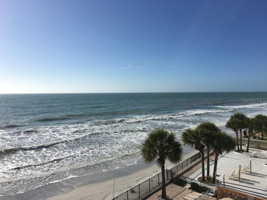 An elevated view of a sandy beach and ocean with palm trees and a patio — 16330 GULF BOULEVARD UNIT 304, REDINGTON BEACH, FL