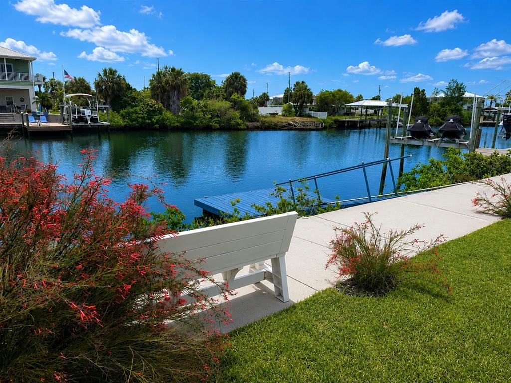 A white bench sits on a concrete patio overlooking a canal with a boat dock — 4502 BAHAMA DRIVE, HERNANDO BEACH, FL