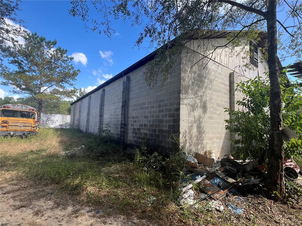 A concrete block building stands next to a yellow school bus and a pile of debris — 4800 CYPRESS STREET, KEYSTONE HEIGHTS, FL