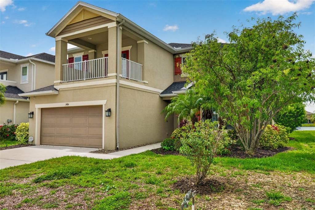 A two-story house with a tan stucco exterior, a two-car garage, and an upper balcony — 5934 ANISE DRIVE, SARASOTA, FL