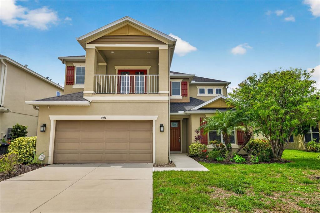 A two-story suburban house features a tan stucco exterior, a two-car garage, and a balcony — 5934 ANISE DRIVE, SARASOTA, FL