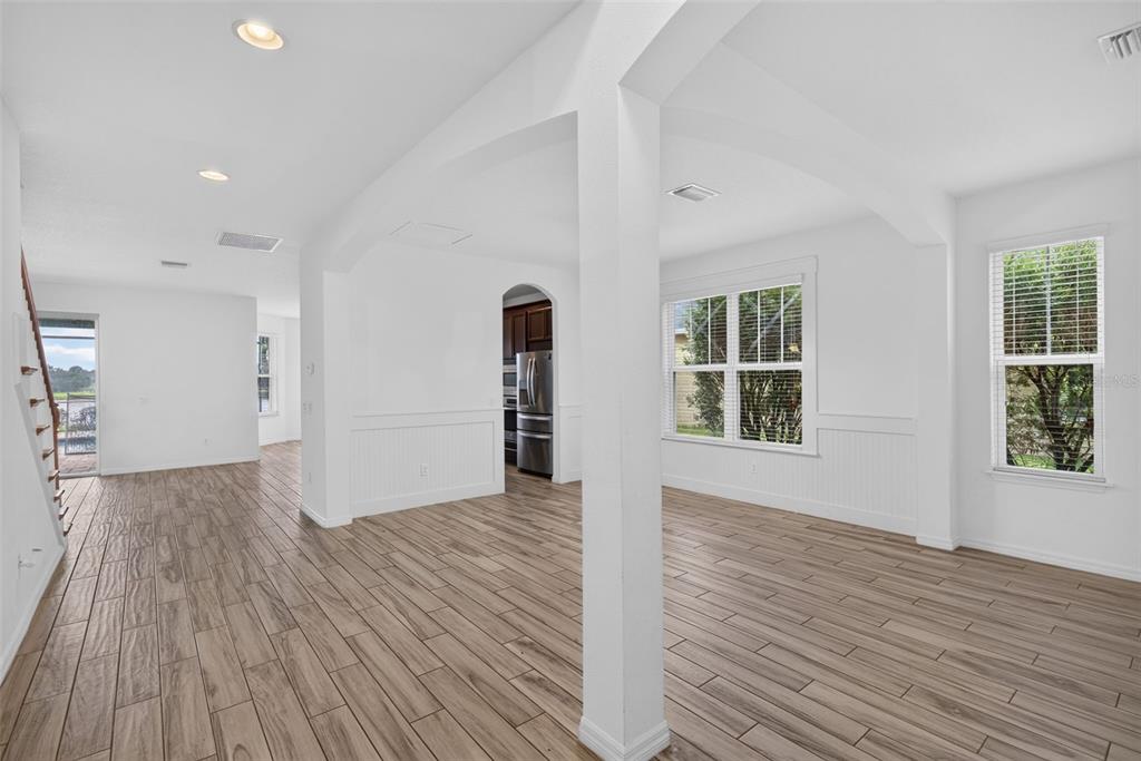 An open-concept living area with wood-look tile flooring, white walls, and a view into the kitchen — 5934 ANISE DRIVE, SARASOTA, FL