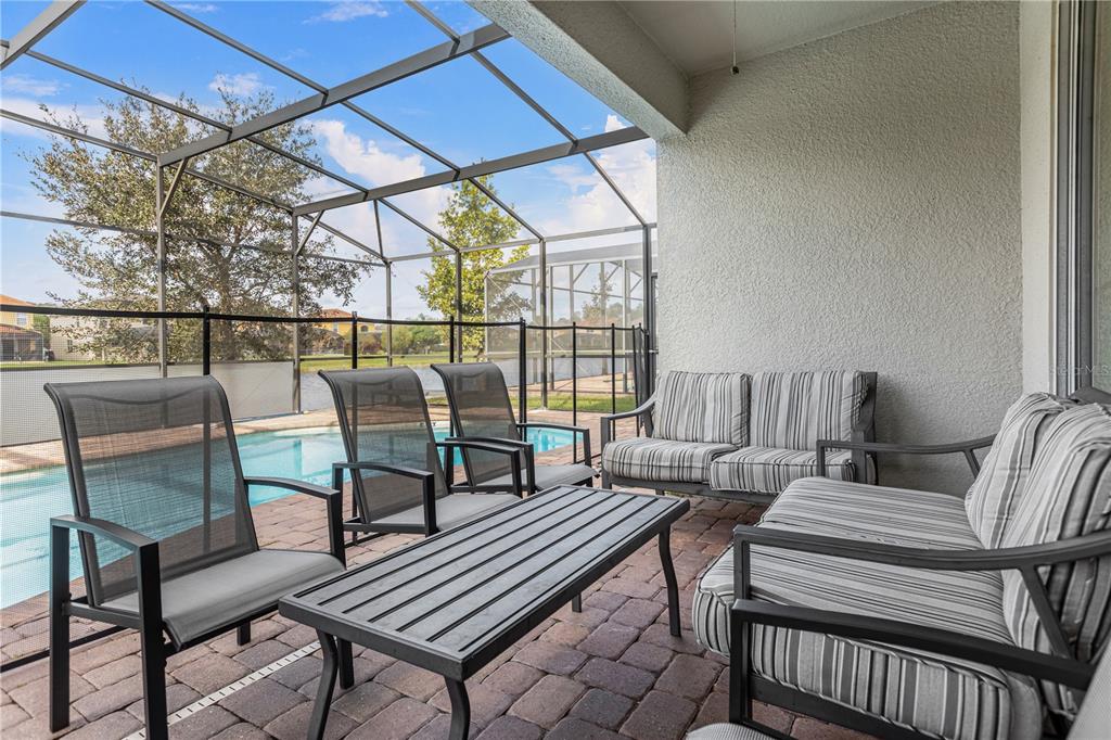 A covered patio features outdoor furniture, a brick floor, and a screened-in pool area — 2580 SHANTI DRIVE, KISSIMMEE, FL