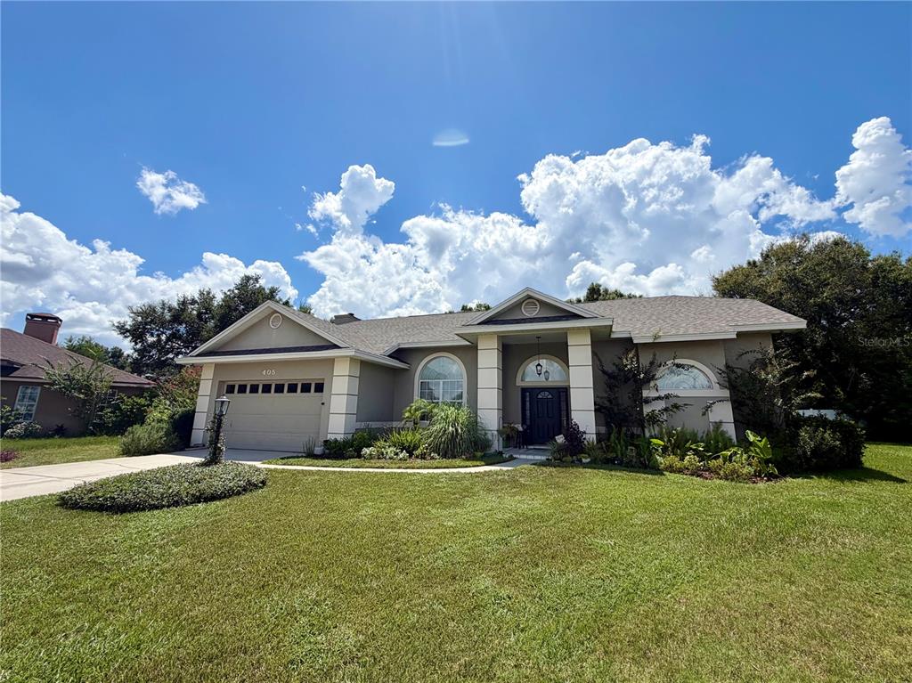 A single-story house with a beige stucco exterior, a two-car garage, and a front porch — 405 VALLEY COURT, WINTER HAVEN, FL