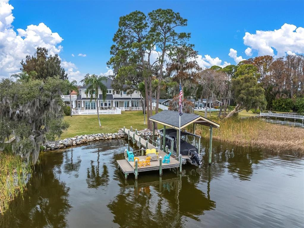 A boat dock with a covered slip sits on a lake in front of a house — 4650 RIDGE VIEW ROAD, PALM HARBOR, FL