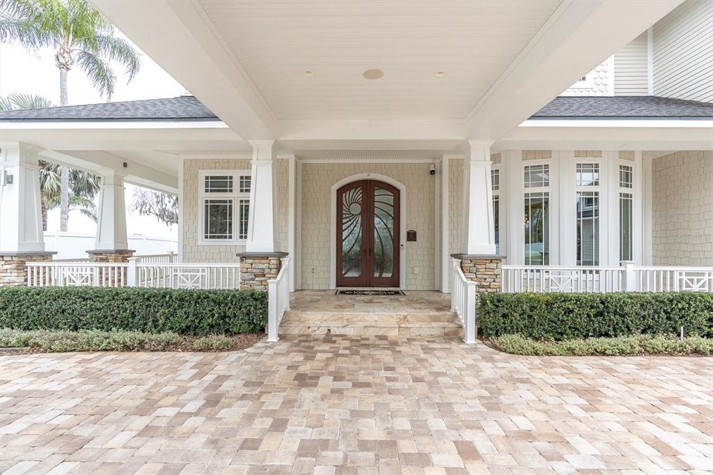 A paved driveway leads to the covered entrance of a house with a wooden door — 4650 RIDGE VIEW ROAD, PALM HARBOR, FL