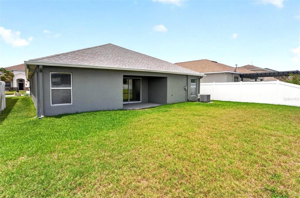 The exterior view shows the gray stucco back wall of a house with a patio — 13128 ROYAL PINES AVENUE, RIVERVIEW, FL