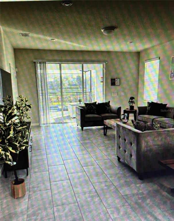 A living room features tile floors, dark furniture, and a sliding glass door to a patio — 7239 OAKMOSS LOOP, DAVENPORT, FL