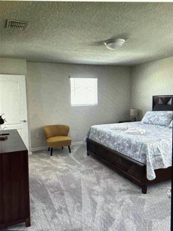 A bedroom features a dark wood bed, a yellow accent chair, and gray carpeting — 7239 OAKMOSS LOOP, DAVENPORT, FL