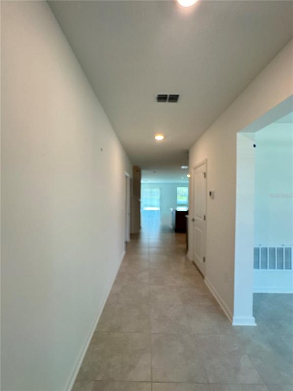 A long hallway with light-colored tile flooring leads toward an open kitchen area — 4039 AMBROSE AVENUE, KISSIMMEE, FL