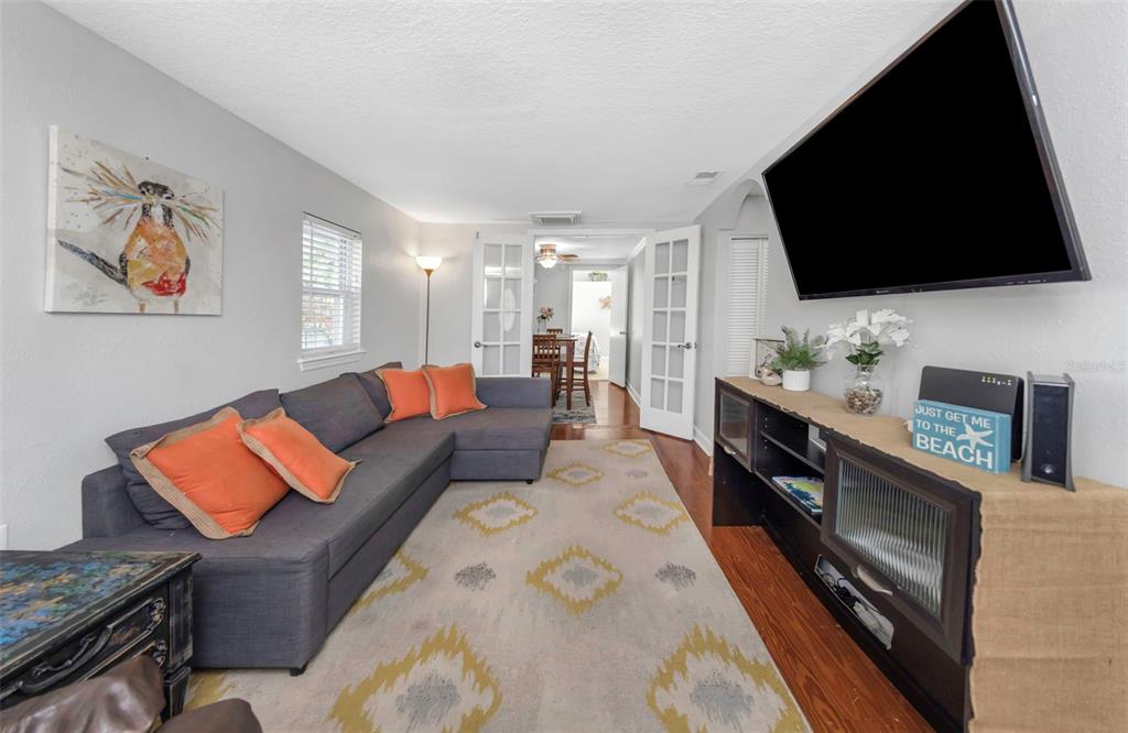 A living room features a gray sofa, a brown recliner, a television, and hardwood floors — 414 TAMPA ROAD, PALM HARBOR, FL