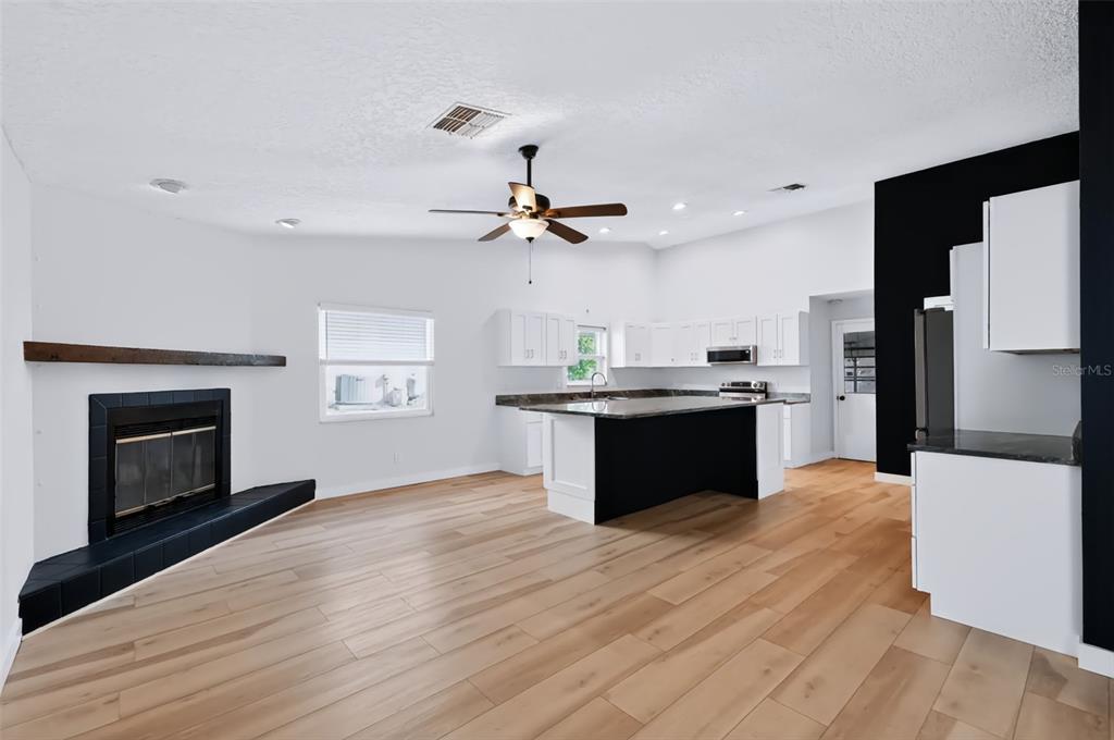 An open-concept kitchen and living area features white cabinets, a blue island, and light wood flooring — 1035 ANCLOTE DRIVE, TARPON SPRINGS, FL