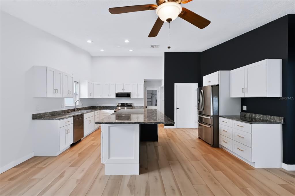 A single-story house with a light blue stucco exterior, a brown garage, and a front lawn — 1035 ANCLOTE DRIVE, TARPON SPRINGS, FL
