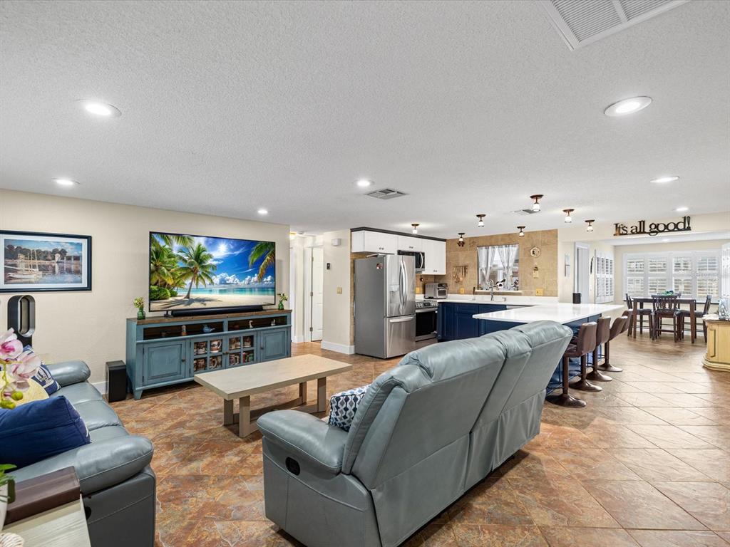A living room and kitchen open-concept space with tile flooring and a blue media console — 13521 VERONICA DRIVE, HUDSON, FL