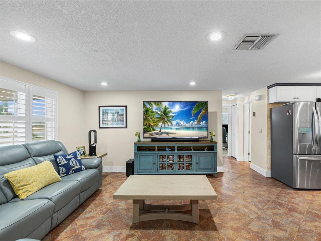 A living room features a blue sofa, a television on a blue console, and tile flooring — 13521 VERONICA DRIVE, HUDSON, FL