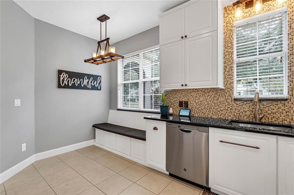 A kitchen breakfast nook features white cabinetry, a built-in bench, and a mosaic tile backsplash — 12543 CRUXBURY DRIVE, WINDERMERE, FL