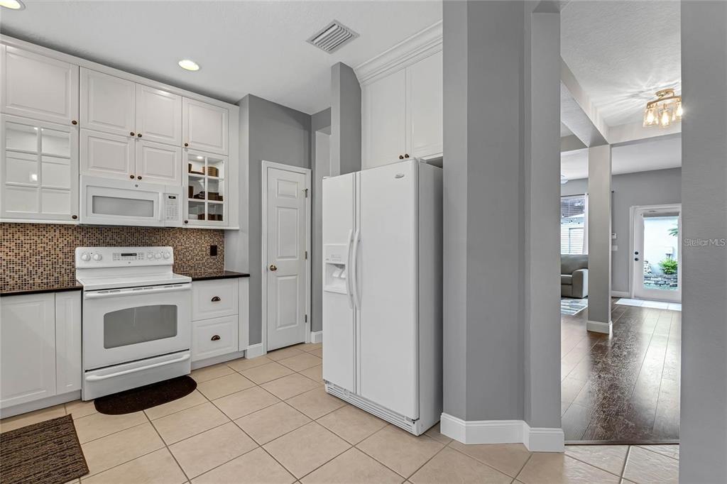 A kitchen features white cabinets, a white refrigerator, a white stove, and tiled flooring — 12543 CRUXBURY DRIVE, WINDERMERE, FL