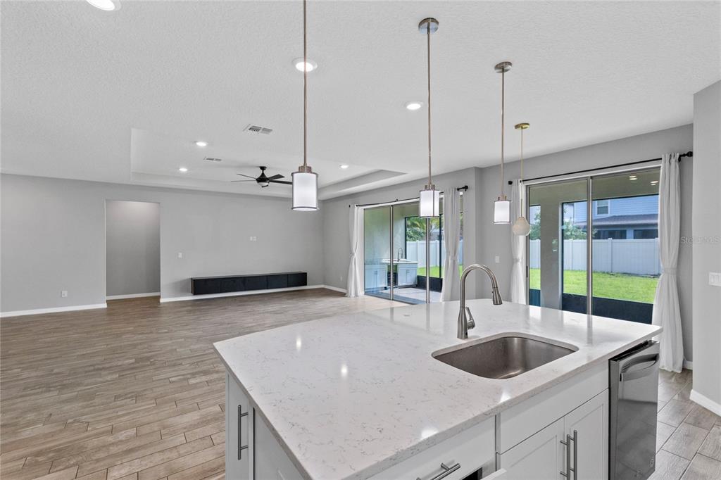 A kitchen island with a sink overlooks an open-concept living area with sliding glass doors — 2754 MATERA DRIVE, ST CLOUD, FL