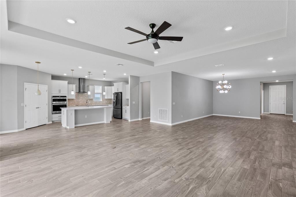 An open-concept kitchen and living area features light wood-look tile flooring and white cabinetry — 2754 MATERA DRIVE, ST CLOUD, FL