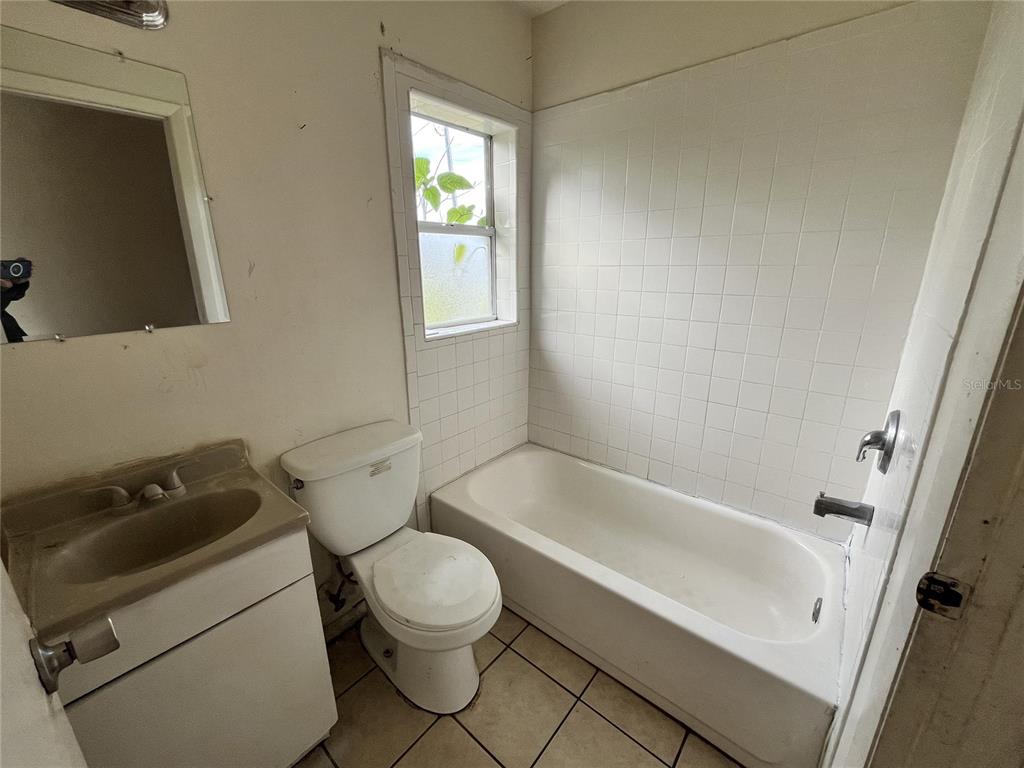 A small bathroom features a vanity, a toilet, and a tiled bathtub shower combination — 311 E MAGNOLIA STREET UNIT 2, LEESBURG, FL