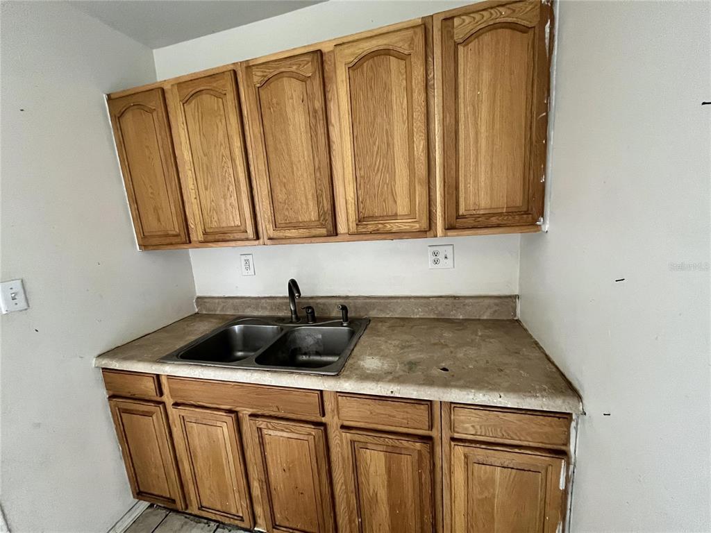A kitchen features wood cabinets, a double-basin stainless steel sink, and a laminate countertop — 311 E MAGNOLIA STREET UNIT 2, LEESBURG, FL
