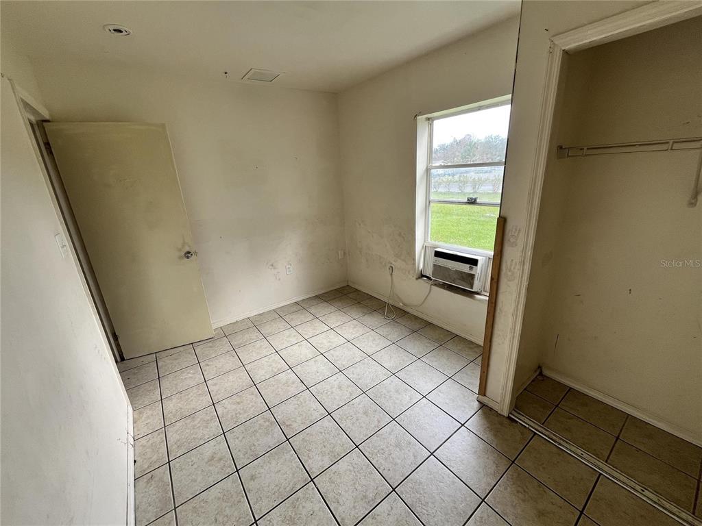 A small room with white walls, tiled flooring, a window air conditioner, and a closet — 311 E MAGNOLIA STREET UNIT 2, LEESBURG, FL