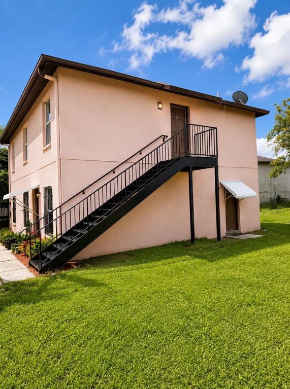 A two-story peach-colored building features an external black metal staircase leading to the upper level — 3212 N 50TH STREET UNIT B, TAMPA, FL