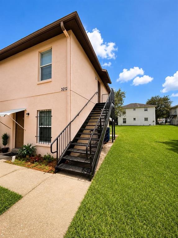 An exterior view of a two-story peach-colored building with an outdoor metal staircase — 3212 N 50TH STREET UNIT B, TAMPA, FL