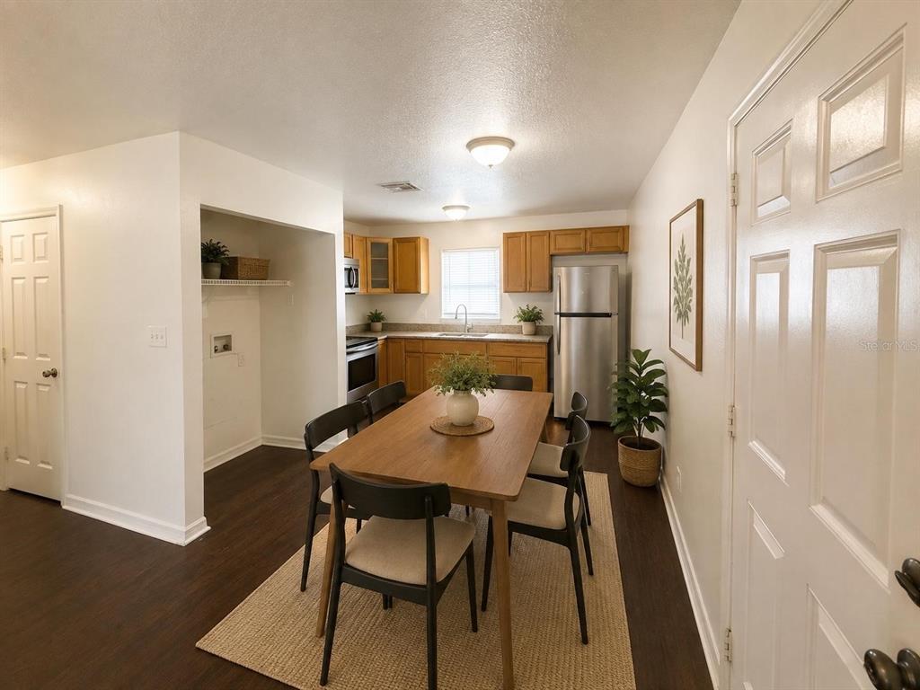 A dining area with a wooden table sits adjacent to a kitchen with wood cabinets — 3212 N 50TH STREET UNIT B, TAMPA, FL