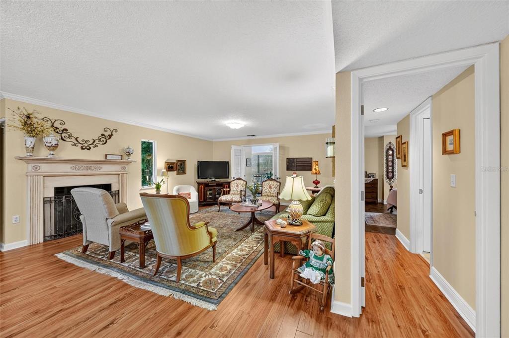 A living room with a fireplace, hardwood floors, and a view into a hallway — 250 CAROLINA AVENUE UNIT 205, WINTER PARK, FL