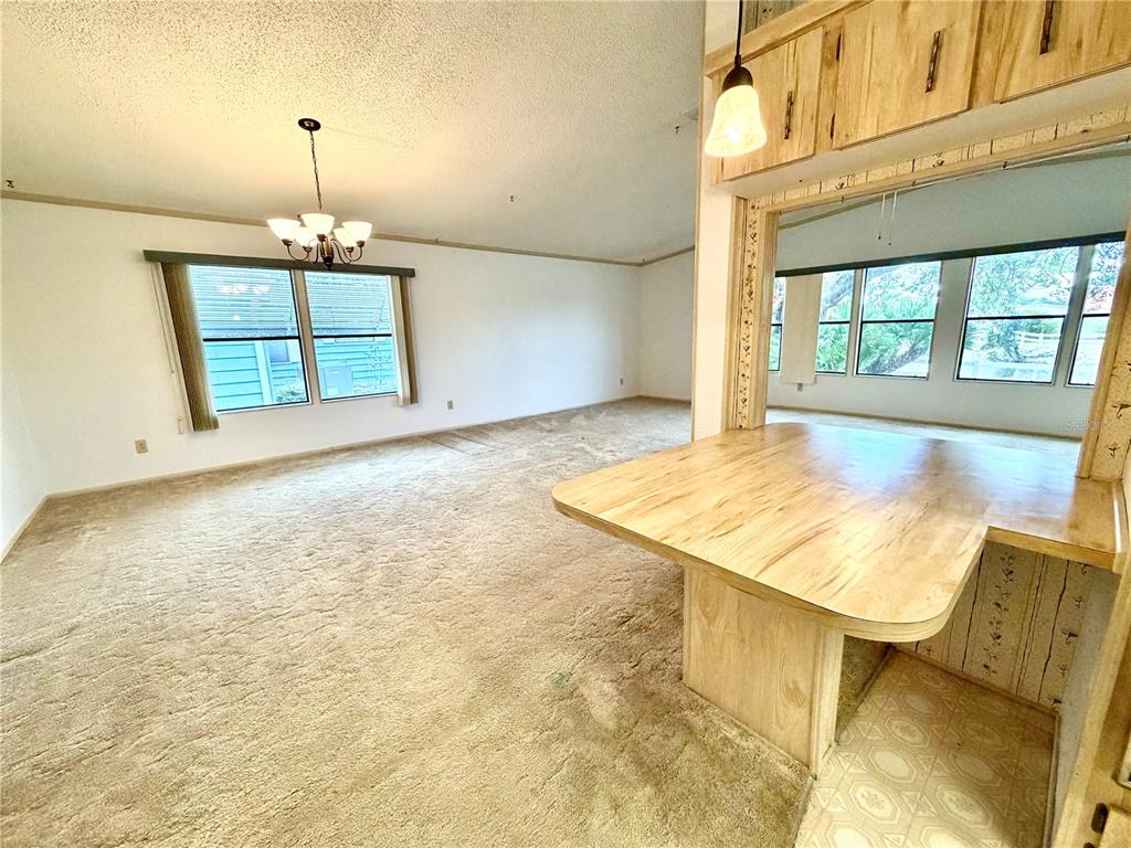 A carpeted living room features a wooden breakfast bar and a view into another room — 3014 RAINBOW ROAD, TAVARES, FL