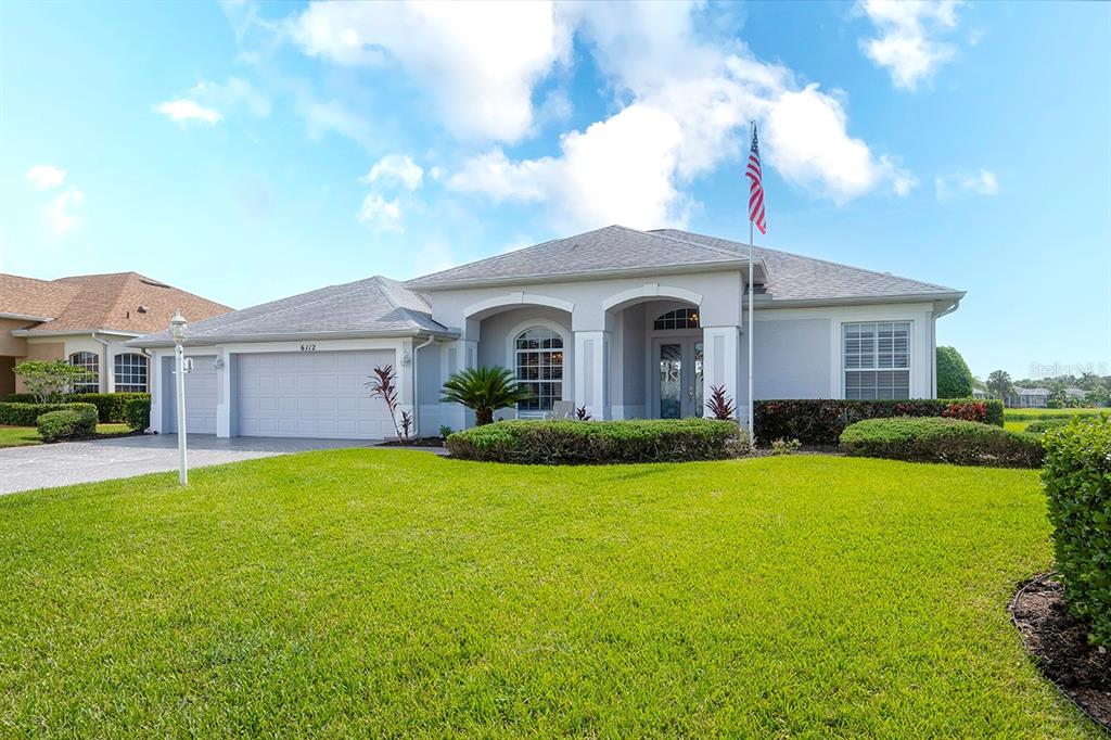 A single-story house with a gray roof, white stucco exterior, and a manicured front lawn — 6112 90TH AVENUE CIRCLE E, PARRISH, FL