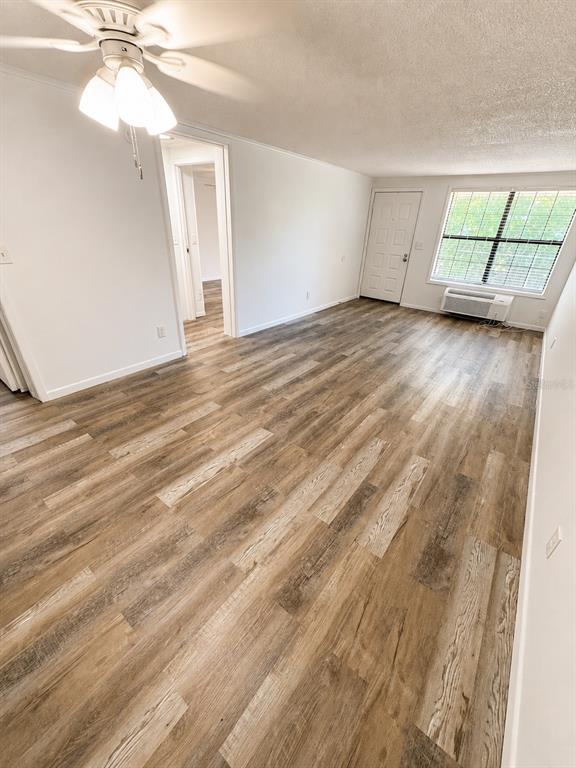 An empty room features wood-look flooring, a ceiling fan, a doorway, and a window unit — 420-420 MILLS STREET UNIT 20, LEESBURG, FL