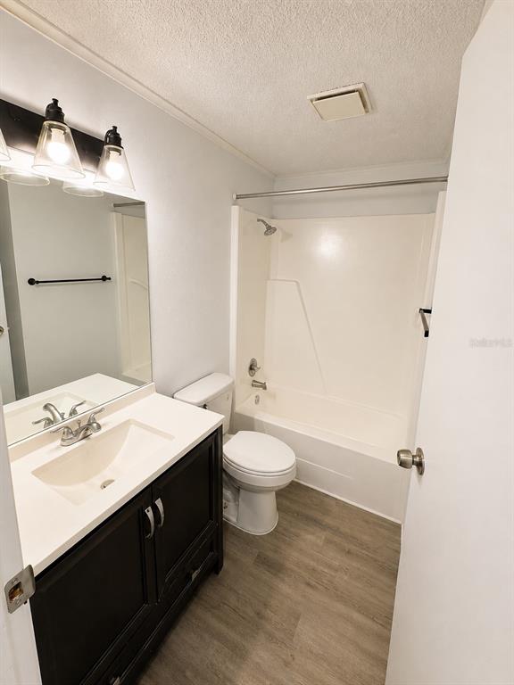 A bathroom features a dark vanity, white countertop, toilet, and a shower-tub combination — 420-420 MILLS STREET UNIT 20, LEESBURG, FL