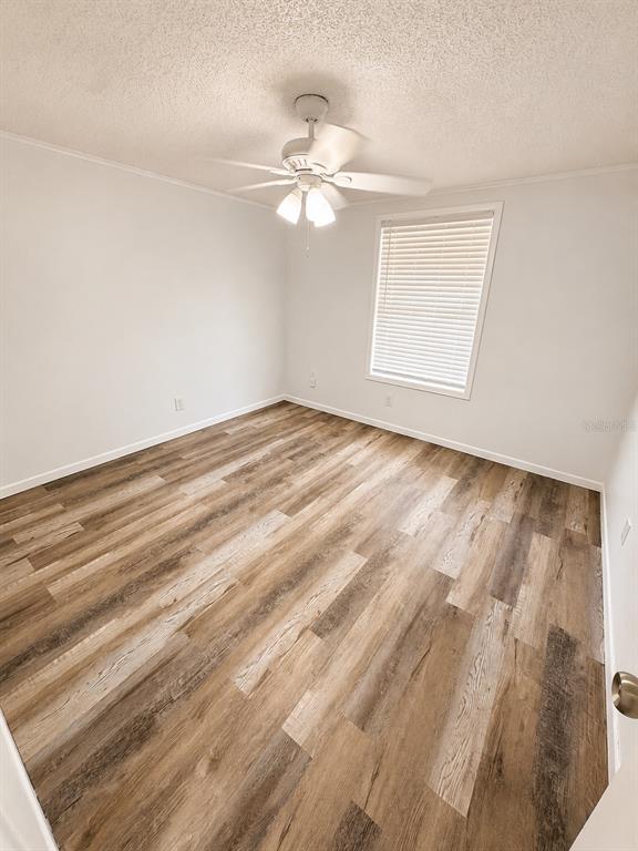 An empty bedroom with light gray walls, wood-look vinyl flooring, and a white ceiling fan — 420-420 MILLS STREET UNIT 20, LEESBURG, FL