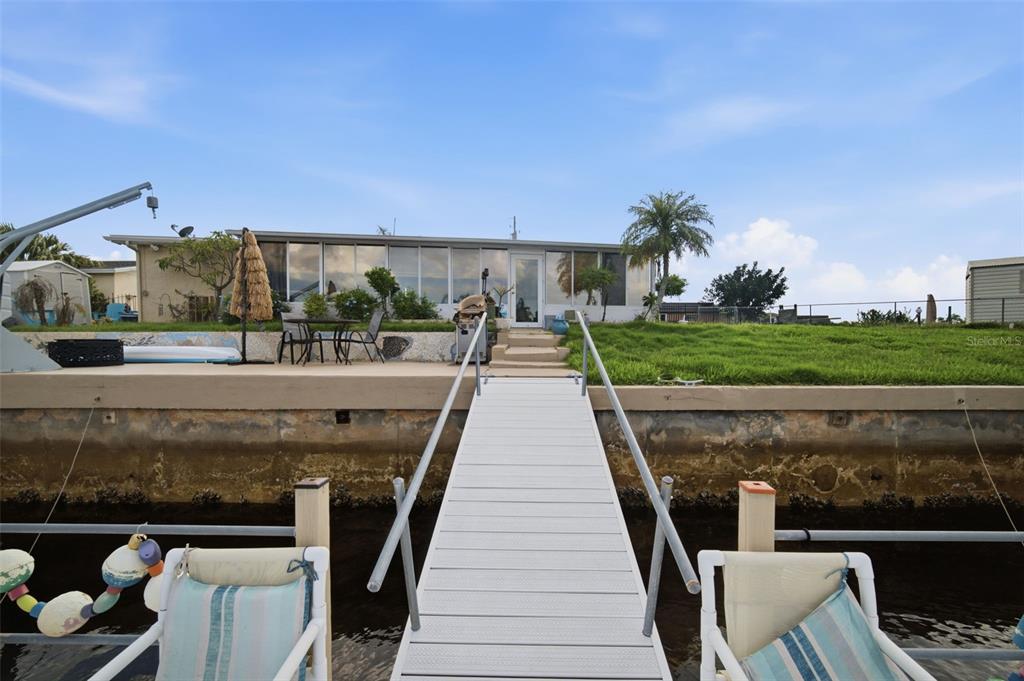 A view from a dock looking toward the backyard and rear exterior of a house — 12816 4TH ISLE, HUDSON, FL
