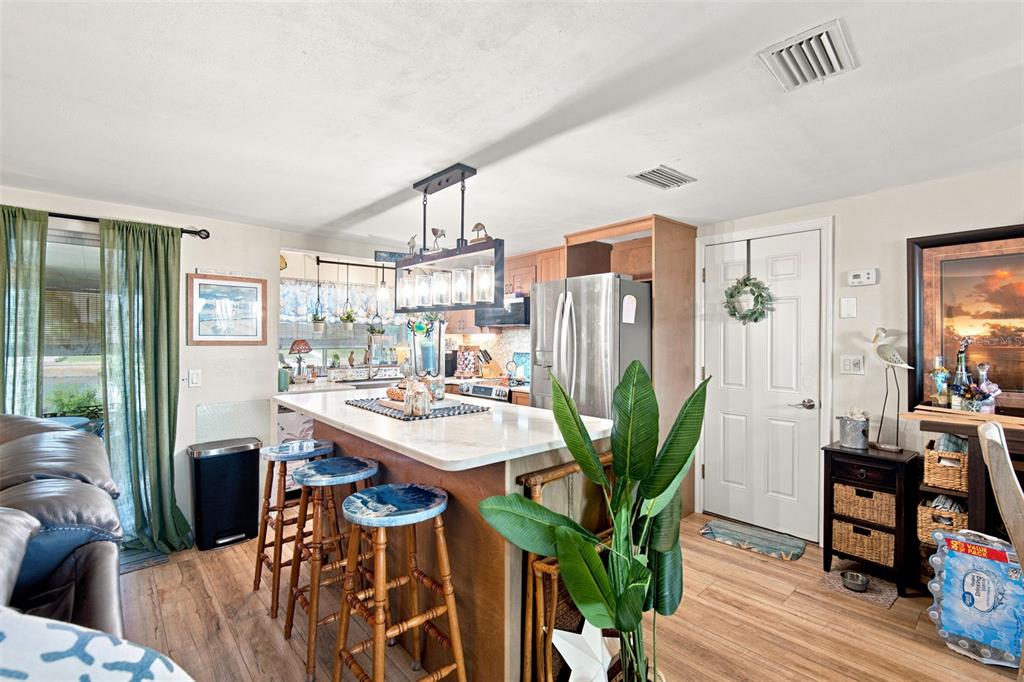 A kitchen features a white island with bar stools, stainless steel appliances, and wood flooring — 12816 4TH ISLE, HUDSON, FL