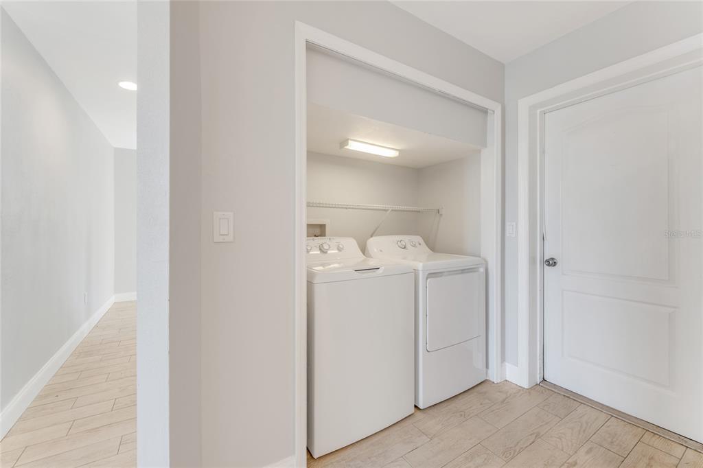 A laundry closet with a white washer and dryer sits beside a closed door — 3070 OCEAN SHORE BOULEVARD, ORMOND BEACH, FL