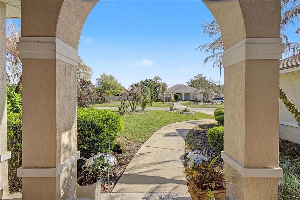 A view from a covered entryway looking out onto a front yard and sidewalk — 11 CRESCENT LAKE WAY, ORMOND BEACH, FL