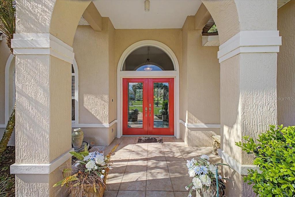 A covered entryway features a red double door with glass panels and an arched transom — 11 CRESCENT LAKE WAY, ORMOND BEACH, FL