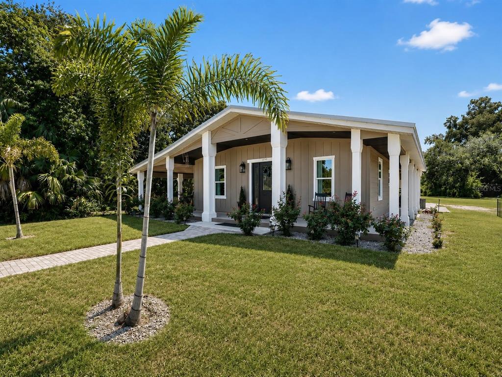A gray front door with sidelights and a wreath is centered on a covered porch — 11740 DARSEY ROAD, PARRISH, FL
