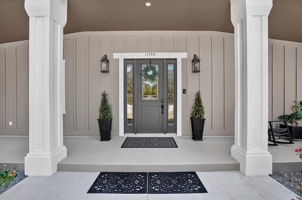 A tan, single-story house with a covered front porch, white columns, and a palm tree — 11740 DARSEY ROAD, PARRISH, FL