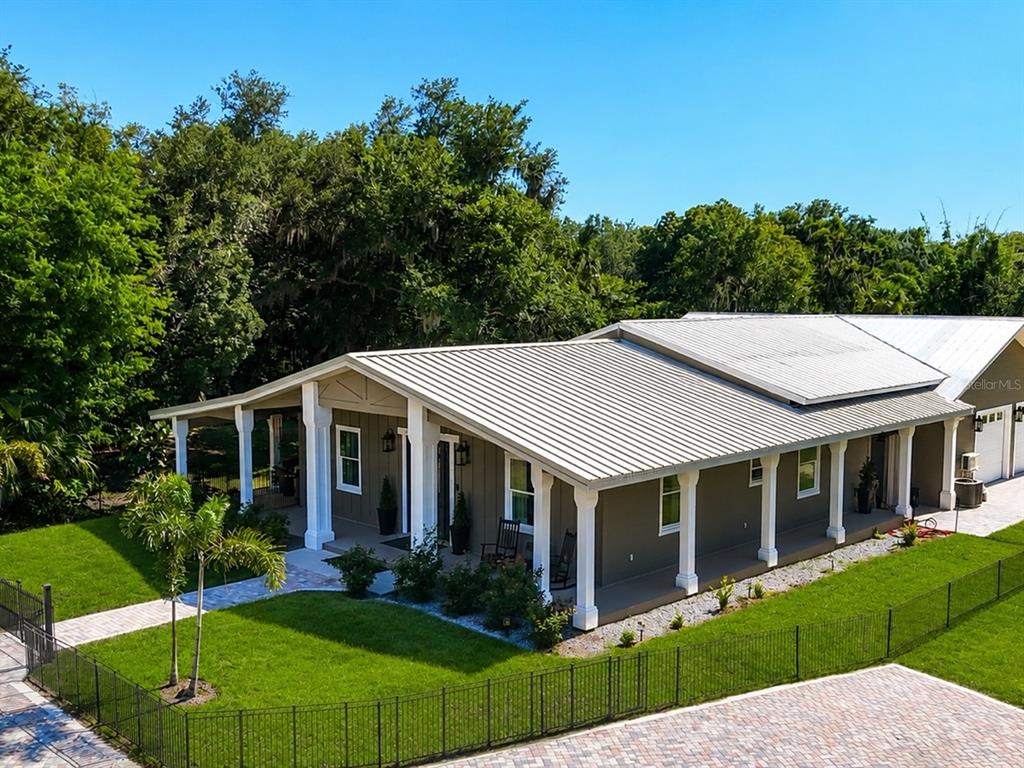 A single-story house with a metal roof and a wide covered porch with white columns — 11740 DARSEY ROAD, PARRISH, FL