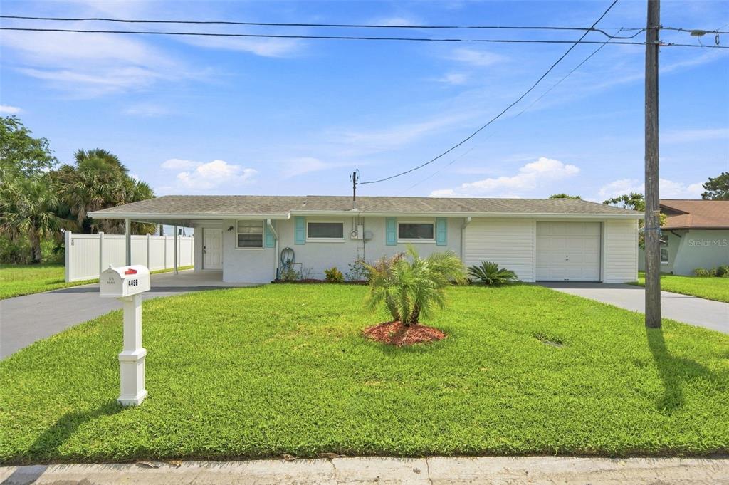 A single-story white house with a carport, garage, and front lawn under a blue sky — 4496 BIMINI DRIVE, HERNANDO BEACH, FL